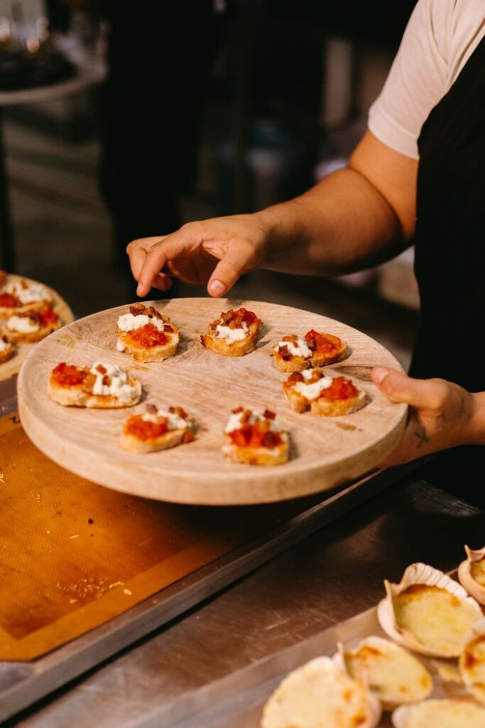 The Art of Drawing Readers In: Your attractive post title goes here Chef elegantly prepares a wooden serving tray with delicious bruschetta appetizers in a kitchen setting.